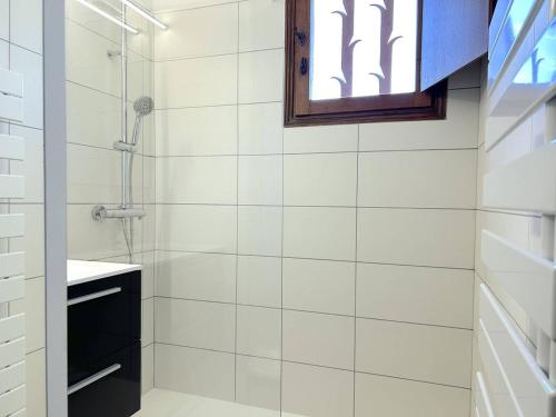 La salle de bains blanche est pourvue d'une douche et d'une fenêtre. dans l'établissement Appartement 2 pièces avec mezzanine et parking, proche plage - Le Lavandou - FR-1-251-205, au Lavandou