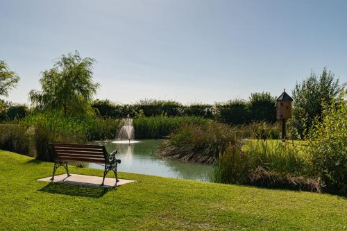 a park bench sitting in the grass next to a pond at The Stables in Firsby