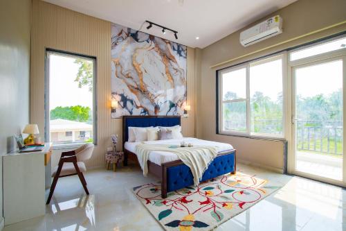 ein Schlafzimmer mit einem Bett, einem Schreibtisch und Fenstern in der Unterkunft ELIVAAS 3 BHK Amber Villa With Pvt Pool, Game Room & Studio Rooms in Dhauj