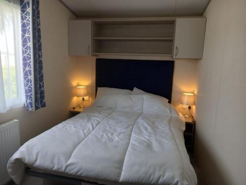 a bedroom with a white bed with two lamps at 33 Unity Beach Pet friendly Pets stay free 3 bedrooms sleeps 8 in Brean
