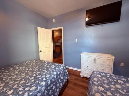 a bedroom with a bed and a dresser and a flat screen tv at Twilight Motel in Wildwood