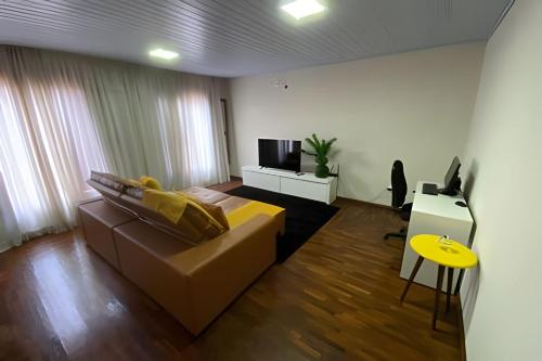 Una sala de estar con un sofá y un televisor. en Casa Ampla - Climatizada - 1 suite-2 quartos-churrasqueira, en Foz do Iguaçu