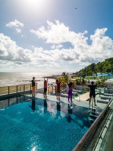 a group of people playing in a swimming pool next to the beach at Hotel Cabo Branco Atlântico in João Pessoa