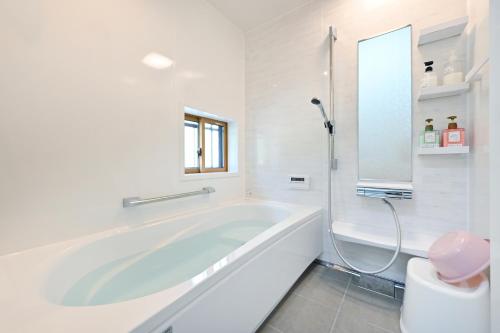 a white bathroom with a tub and a toilet at 峠のお宿 巧の実家 Magome Guest House, Along the Nakasendo Trail in Nakatsugawa