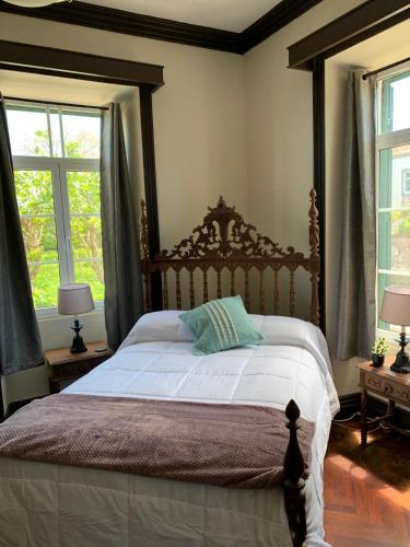 a bedroom with a large bed with two windows at Cozy Nest in Bretanha