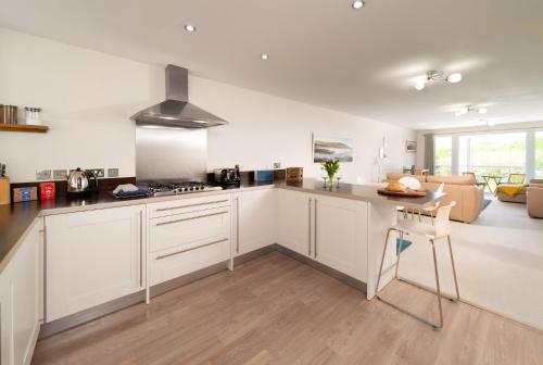 a kitchen with white cabinets and a living room at 6 Bluestone Point in Mortehoe