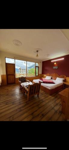 a large bedroom with two beds and a large window at Mountain Face cottage and Resort in Manāli