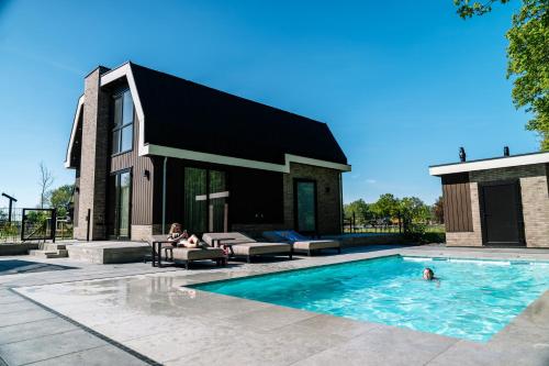 a house with a swimming pool with two people in it at Vakantierijk Waarland in Waarland