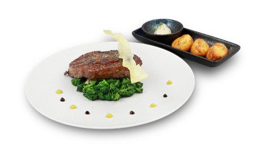 a white plate with a piece of meat and vegetables at Hotel An der Wasserburg in Wolfsburg