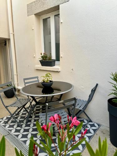 a table and chairs on a patio with flowers at Suite Au grand air in Châteauneuf-du-Faou