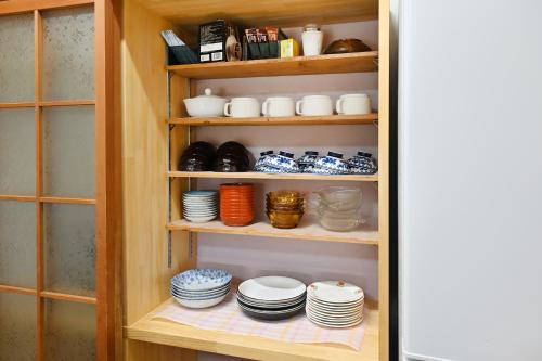 a pantry with plates and bowls on shelves at 峠のお宿 巧の実家 Magome Guest House, Along the Nakasendo Trail in Nakatsugawa