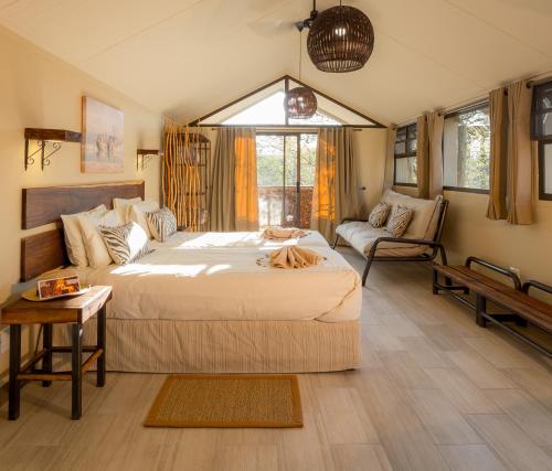 a bedroom with a large bed and a couch at Etosha Village in Okaukuejo