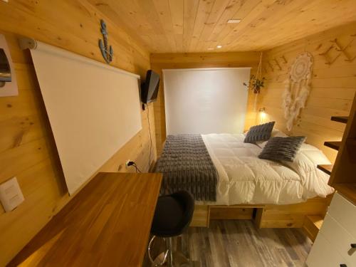 a bedroom with a bed in a wooden room at Hostal Kuyen in Pichilemu