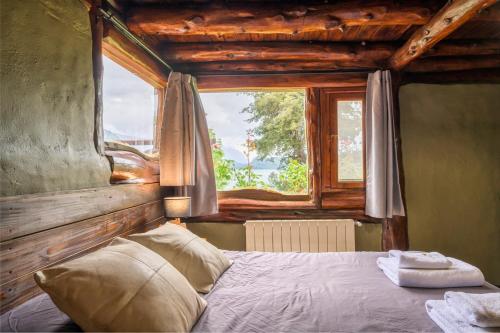 a bedroom with a bed in front of a window at Cabañas Villa Labrador con costa de lago in San Carlos de Bariloche