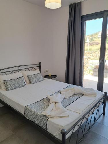 a bed in a bedroom with a large window at Terracotta Sunset Naxos in Galanádhon