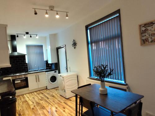 a living room with a table and a kitchen at Double-Bedroom in the Heart of Harpurhey Manchester A2 Perfect for Short Stays in Manchester