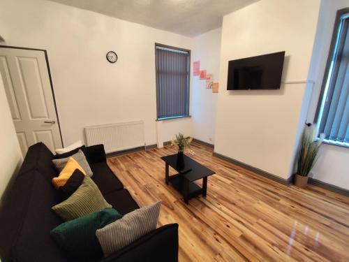a living room with a couch and a flat screen tv at Double-Bedroom in the Heart of Harpurhey Manchester A2 Perfect for Short Stays in Manchester