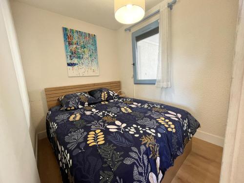 une chambre avec un lit avec une couette bleue et une fenêtre dans l'établissement Le Wharf, à Seignosse