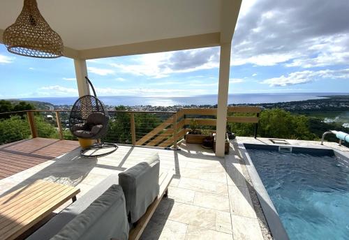 a house with a swimming pool and a patio with a swing at Villa Perle de l'ouest - piscine et vue mer 180 sur la baie de St-Paul in Saint-Paul