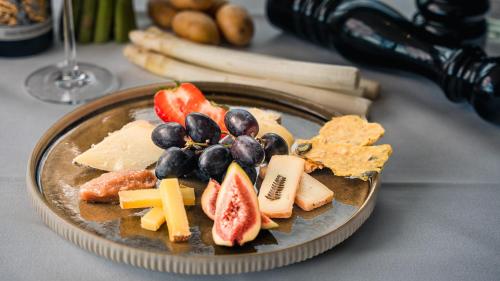a plate of food with cheese and fruit on a table at Hotel An der Wasserburg in Wolfsburg