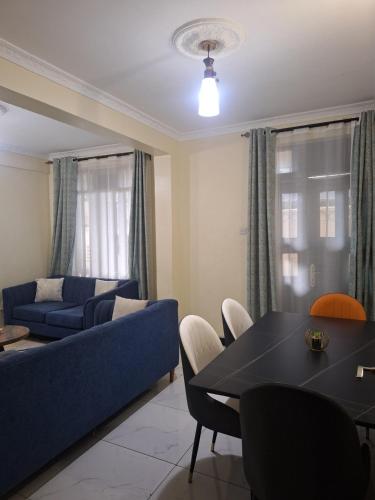 a living room with a blue couch and a table at Angies staycation 2br apt Milimani in Kisumu