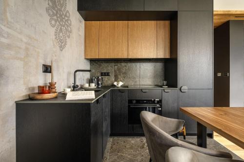 a kitchen with black cabinets and a wooden table at Landscape Villas - LoftAffair Spa Collection in Kościelisko