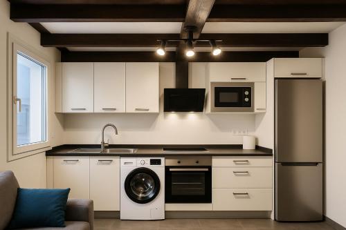 a kitchen with white cabinets and a washer at Apartamento en pleno centro de León para 4 personas in León