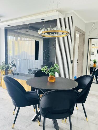 a dining room with a black table and chairs at Apartamenty BLUE BALTIC SPA Jacuzzi & Sauna MORZE in Chłopy
