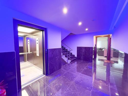 a room with purple walls and stairs with a glass door at Blue Star Suites by SDR in Paralia Katerinis