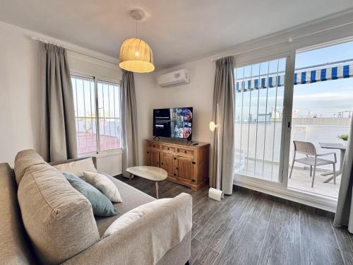 a living room with a couch and a large window at Apartamentos Turísticos Santo Rostro in Chipiona