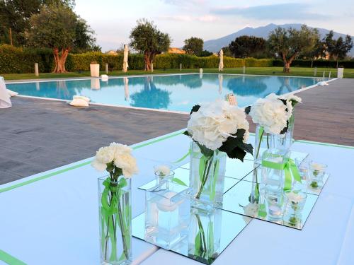 two vases filled with flowers on a table next to a swimming pool at Pietrabianca Exclusive Resort in Pomigliano dʼArco