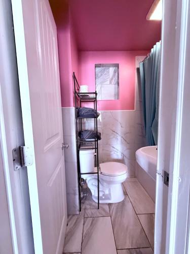 a bathroom with a toilet and a pink wall at Twilight Motel in Wildwood