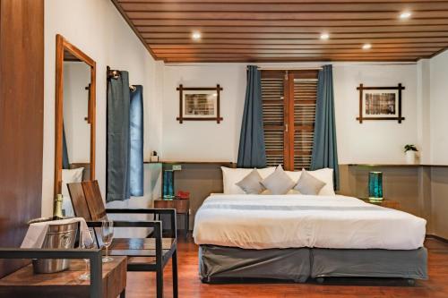 a bedroom with a large bed and a table at Sanctuary Hotel Luang Prabang in Luang Prabang
