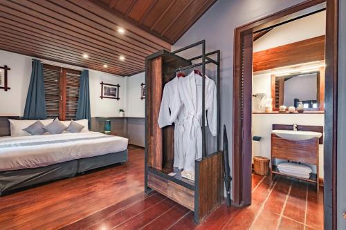 a bedroom with a bed and a mirror and a sink at Sanctuary Hotel Luang Prabang in Luang Prabang