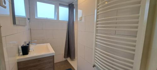 un bagno bianco con lavandino e doccia di Stijlvol chalet Zeeland - Sauna & omheinde tuin VP082 a heinkenszand