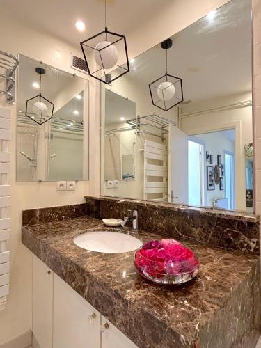 une salle de bain avec un lavabo et un grand miroir dans l'établissement L'appartement Michelangelo, à Paris