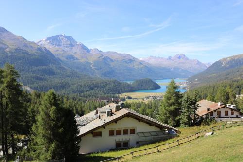 a house on a hill with mountains in the background at Hotel Schweizerhof St. Moritz in St. Moritz