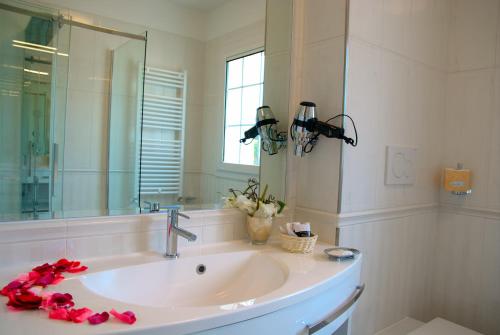 a bathroom with a sink and a mirror and red roses at Hotel La Goletta in Lignano Sabbiadoro