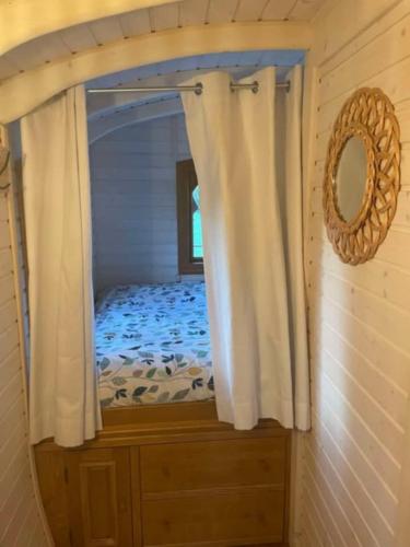 une chambre avec un lit avec un miroir et une fenêtre dans l'établissement Roulotte de charme, à Villers-sur-Authie