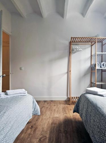 two beds in a room with white walls and wooden floors at Cal Moline 2 Estel in Aviá