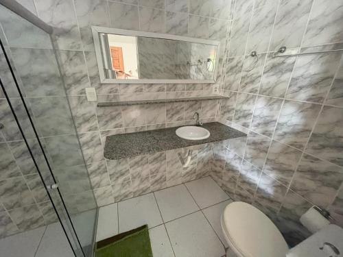 un bagno con un water, un lavandino e uno specchio di Casa de Praia em Sonho verde a Paripueira