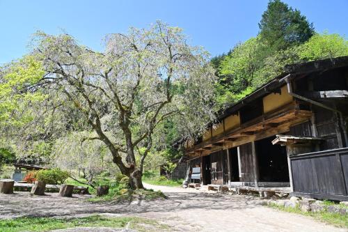 a tree in front of a building next to a building at 峠のお宿 巧の実家 Magome Guest House, Along the Nakasendo Trail in Nakatsugawa