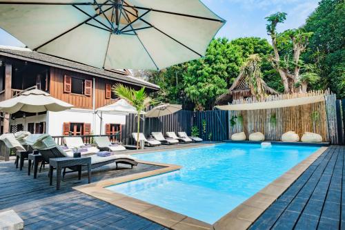 an outdoor pool with chairs and an umbrella at Sanctuary Hotel Luang Prabang in Luang Prabang