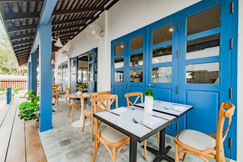 a restaurant with blue doors and tables and chairs at Sanctuary Hotel Luang Prabang in Luang Prabang