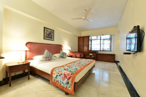 a bedroom with a bed and a ceiling fan at Hotel Parle International in Mumbai