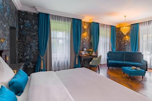 a bedroom with a large bed and a blue couch at Schloßhotel Althörnitz in Bertsdorf