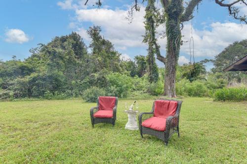 two chairs with red cushions sitting in a field at 2 Mi to Dtwn Spacious Angleton Home with Courtyard! in Angleton