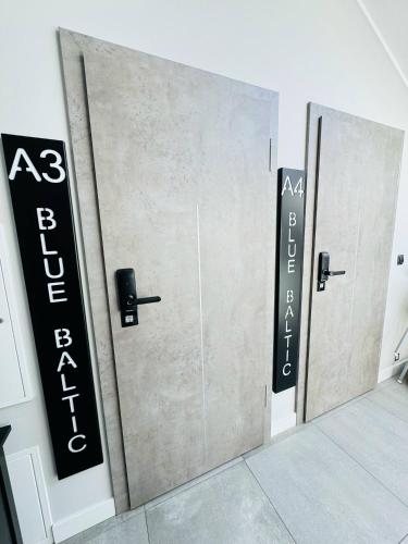 a row of three doors with signs on them at Apartamenty BLUE BALTIC SPA Jacuzzi & Sauna MORZE in Chłopy