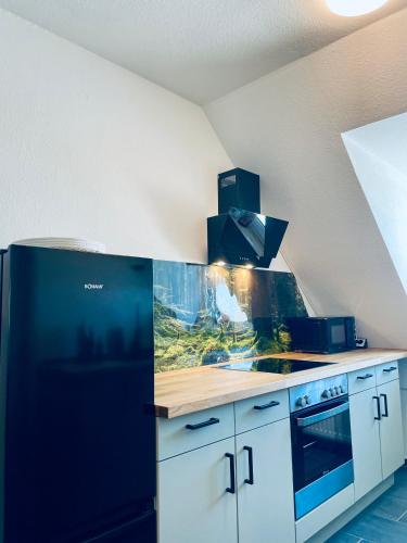 a kitchen with a black refrigerator and white cabinets at Ferienwohnung Seelenliebe in Kevelaer