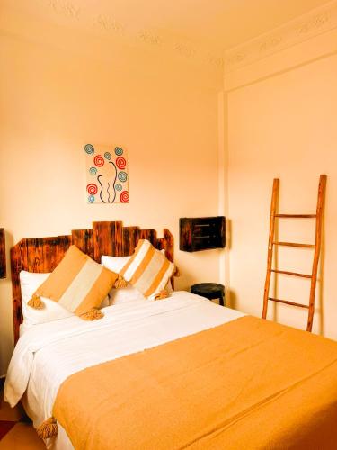 a bedroom with a bed with white sheets and a ladder at Olas Surf Camp in Imsouane